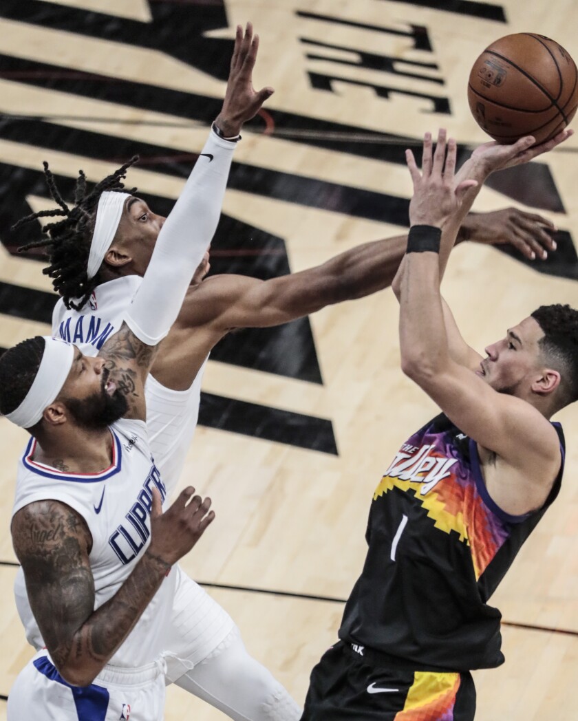 Clippers guard Terance Mann and forward Marcus Morris defend on a shot by Phoenix guard Devin Booker on June 20, 2021.
