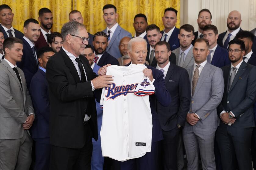 El mánager de los Rangers de Texas Bruce Bochy y los integrantes del equipo le entregan una camiseta del equipo al presidente Joe Biden durante la visita del club a la Casa Blanca para celebrar el campeonato de la Serie Mundial el jueves 8 de agosto del 2024. (AP Foto/Evan Vucci)