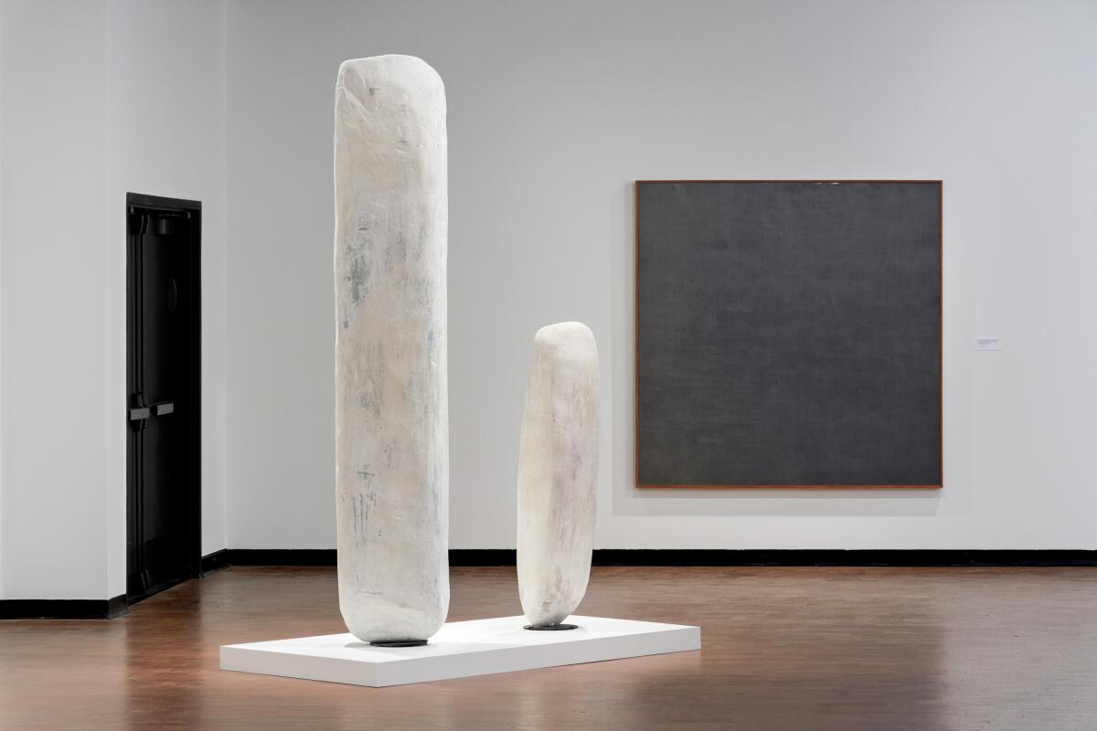 Two white vertical stones displayed at a museum. 