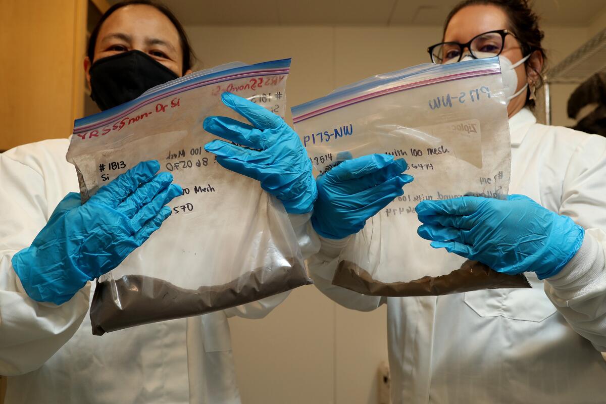 Public Health professors Jun Wu and Alana LeBron hold bags of soil from a community in Santa Ana.