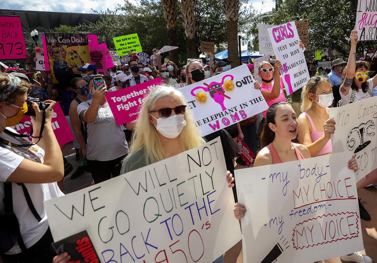 Participants wave signs as they walk back to Orlando City Hall during the March for Abortion Access in Orlando, Fla.