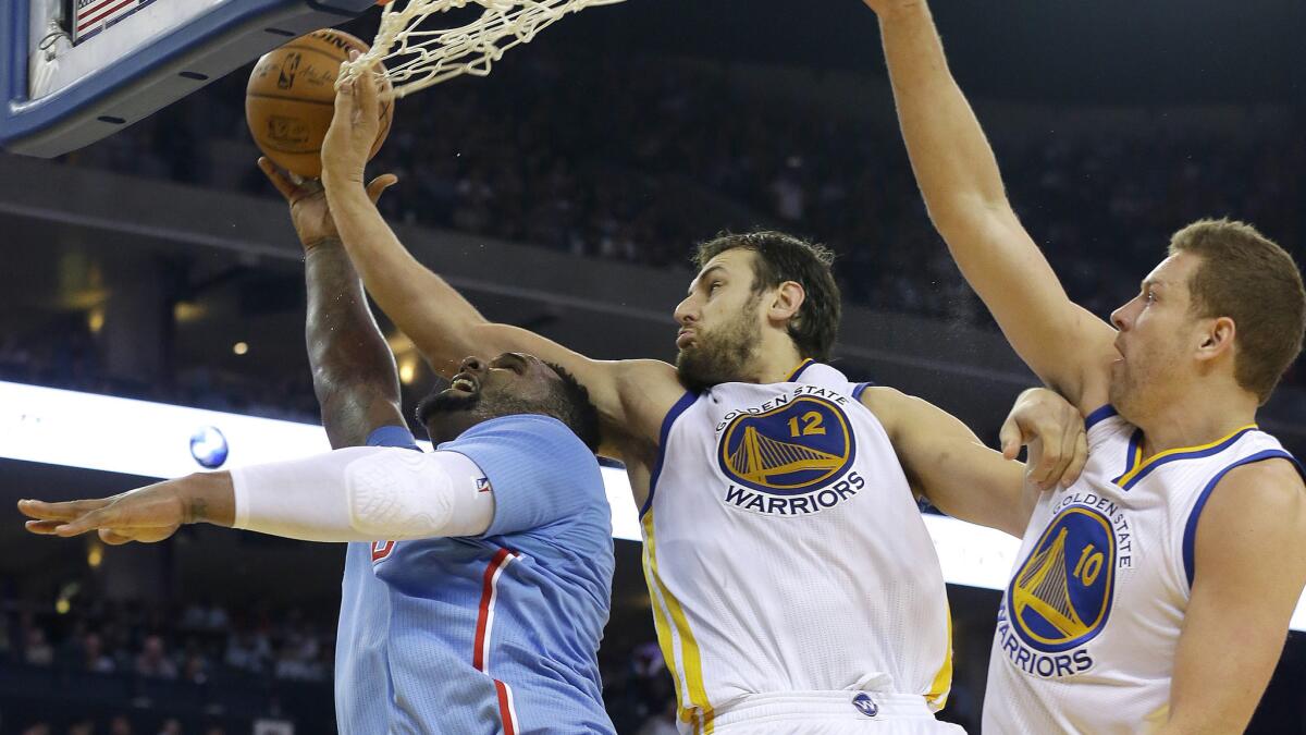 Clippers forward Glen Davis, left, shoots over Golden State Warriors center Andrew Bogut, middle, and forward David Lee during the first half of a game on March 8, 2015.