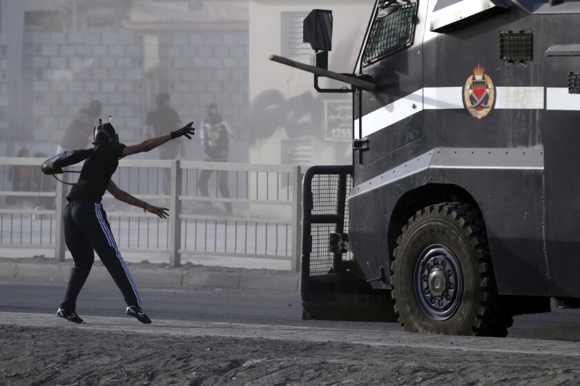 File - In this Friday, March 15, 2013 file photo, a Bahraini anti-government protester throws a piece of wood at an armored police vehicle during clashes in Jidhafs, Bahrain. A decade ago, against all odds, a popular uprising convulsed the monarchy of Bahrain as a wave of revolutionary protests swept across the Middle East. But after a brutal crackdown and years of escalating repression, activists say the small kingdom is less free now than even before the Arab Spring, as authorities crush hopes for political reform. (AP Photo/Hasan Jamali, File)