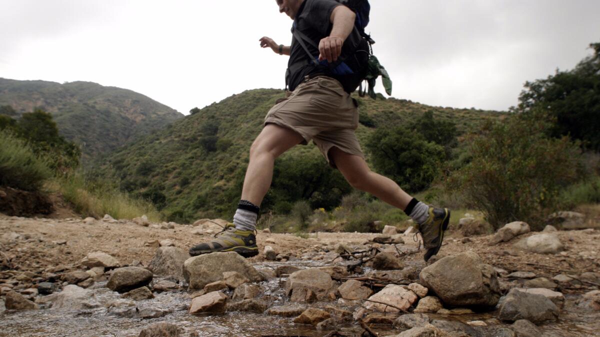 A hiker crosses a stream along the Sam Merrill Trail, where a 69-year-old woman died Sunday while hiking.