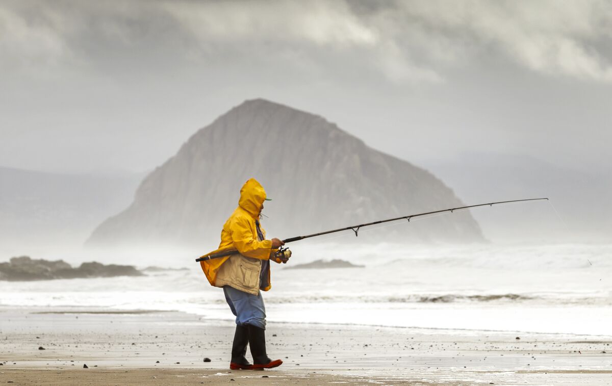 FILE - A fisherman casts his line into the surf north of Morro Rock on Jan. 5, 2016, in Morro Bay, Calif. RV camping may be experiencing a surge in popularity, but not in one California coastal destination. The Morro Bay City Council this week voted 4-1 to end a pilot program that created 19 RV campsites on the waterfront overlooking Morro Rock, a volcanic remnant that rises dramatically on the coast between Los Angeles and the San Francisco Bay Area. (Joe Johnston/The Tribune of San Luis Obispo, File)/The Tribune (of San Luis Obispo) via AP)
