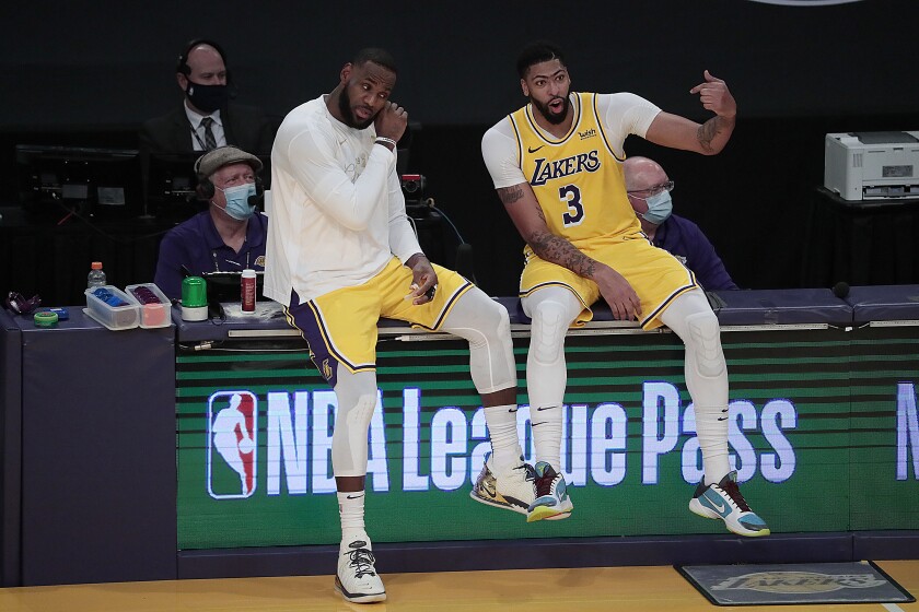 Lakers forwards LeBron James and Anthony Davis sit on the scorer's table whle waiting to check in.