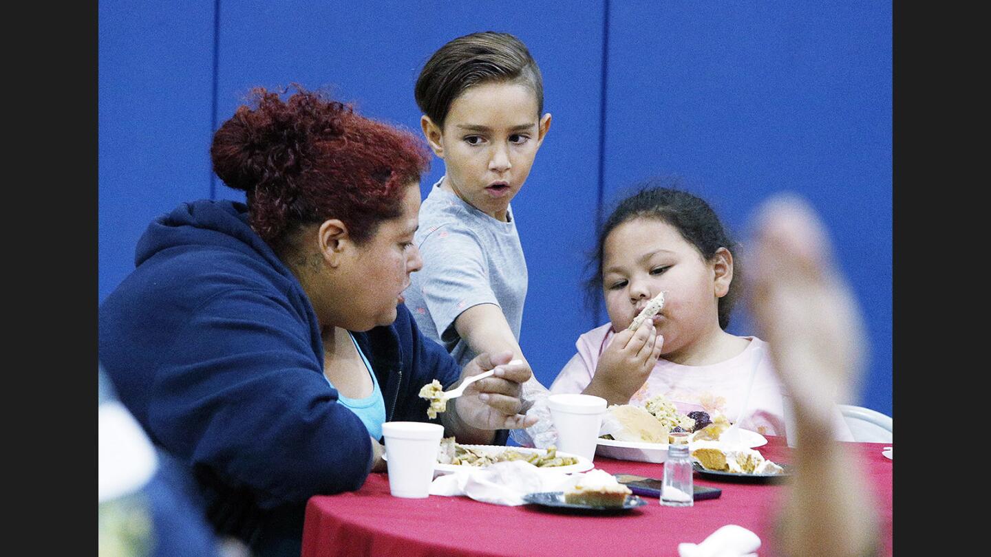 Joseph Waber, 8, of Burbank, serves cups of juice to Christina Urkuilla, of Pacoima, and Rosemary De Albe, 5, of Pacoima, at the Salvation Army in Burbank where a pre-Thanksgiving meal was served on Wednesday, November 22, 2017.