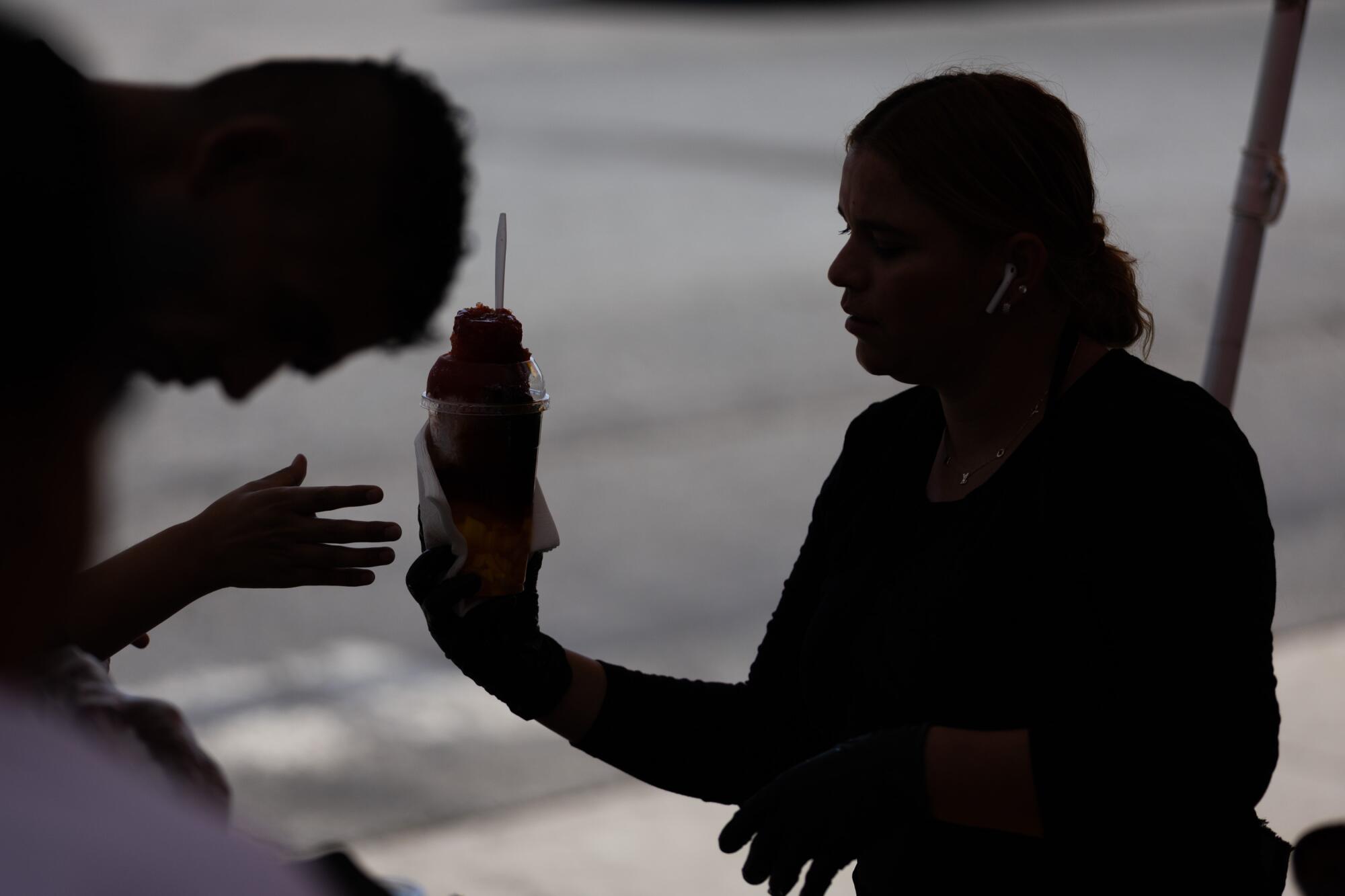 Karina Cerón, de 31 años, sirve un raspado a un cliente durante un día laboral en el que el 