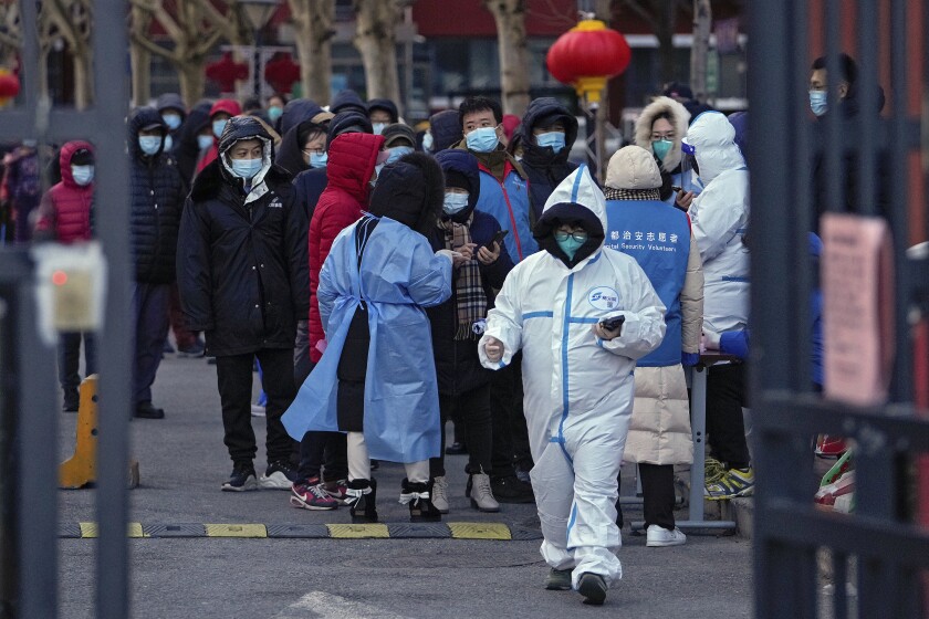 Residentes, con mascarilla para protegerse del coronavirus, esperan en fila para someterse a una prueba de detección del COVID-19 en un centro habilitado en el exterior de un bloque residencial en el distrito de Fengtai, en Beijing, el 26 de enero de 2022. (AP Foto/Andy Wong)