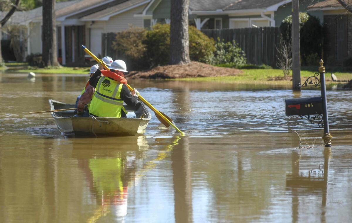 Energy workers use a boat to turn off power in flooded houses in the Canton Club Circle subdivision in northeast Jackson, Miss.