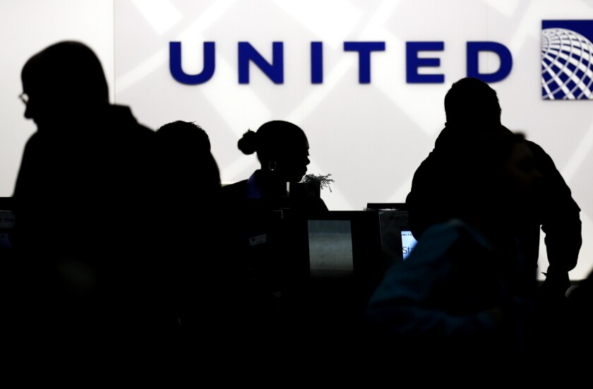 Holiday travelers check in at the United Airlines ticket counter at Chicago's O'Hare International Airport in December 2013. The airline has been fined $2.75 million for violating rules regarding the treatment of passengers with disabilities and keeping passengers stranded on delayed flights more than three hours.