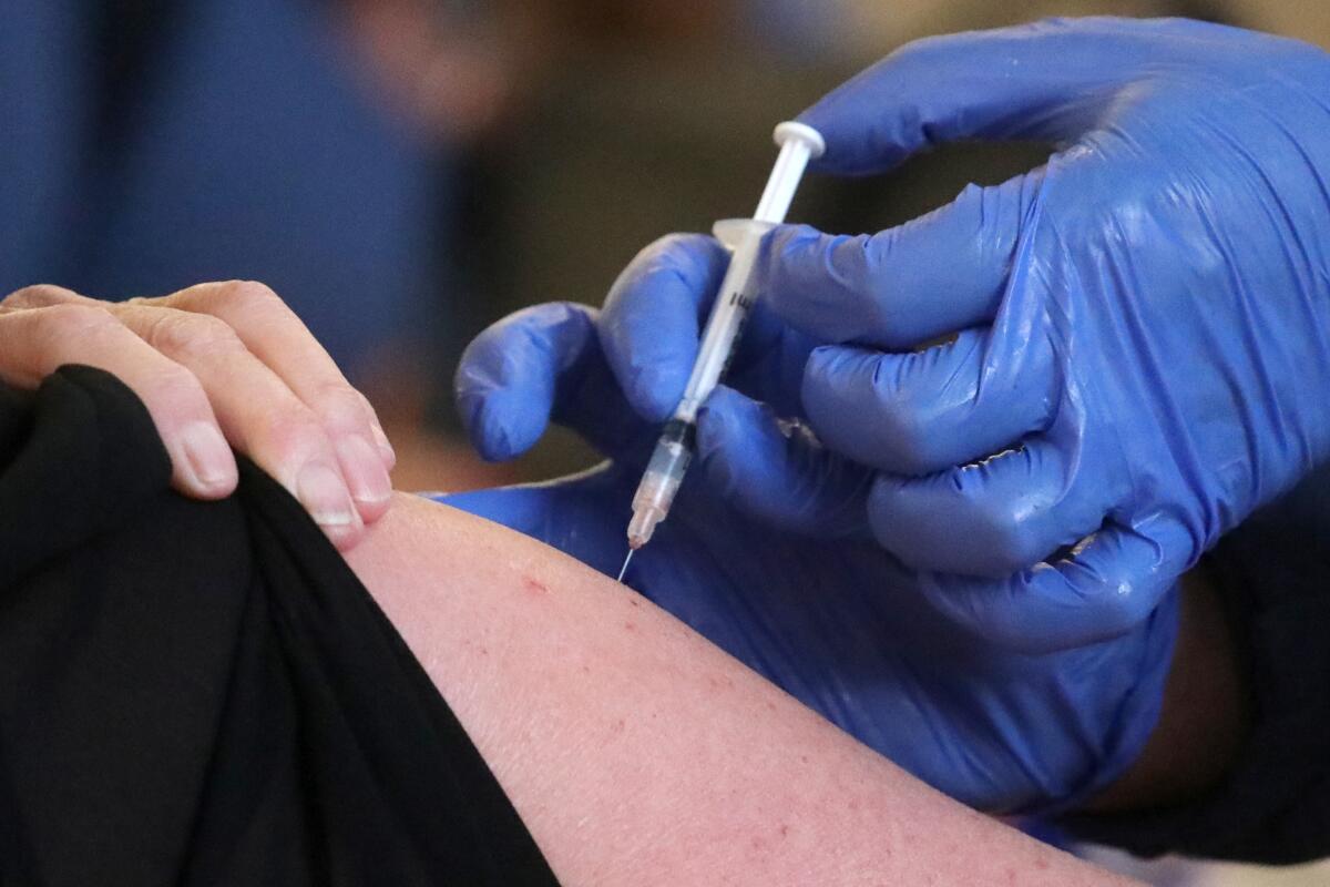 A gloved healthcare worker gives someone a vaccine.