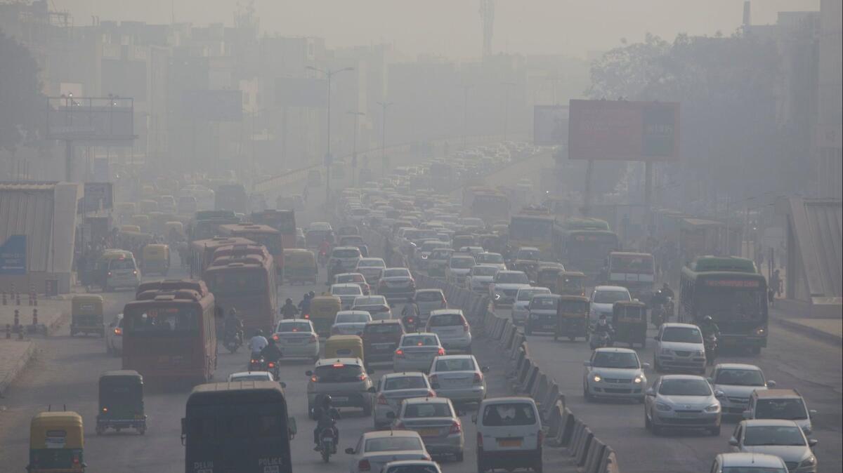 Indian commuters drive amid heavy smog along a busy road in New Delhi in December 2018.