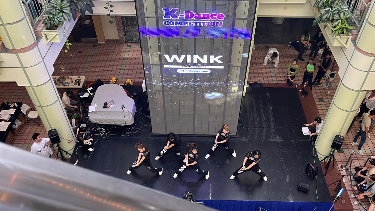 An overhead shot of a dance crew dressed in black Nike outfits performing onstage.