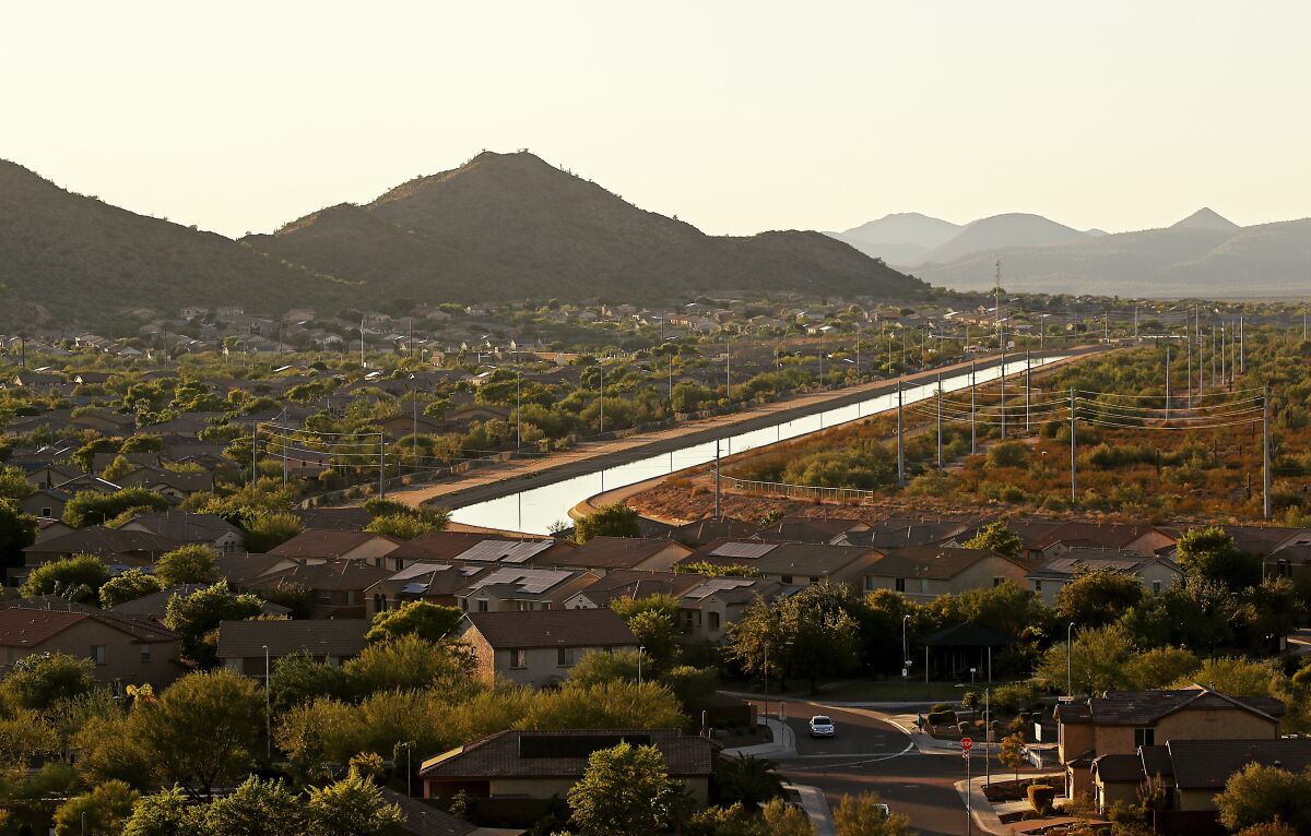 A canal cuts through a suburban desert neighborhood as the sun begins to set