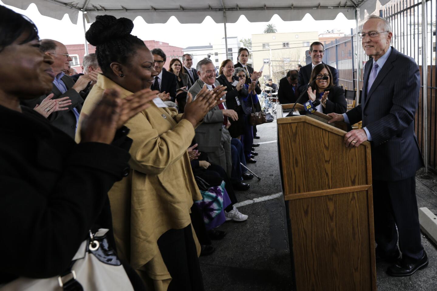 Ron Olson, right, gets a standing ovation at the groundbreaking ceremony of the Ron Olson Justice Center, named after him, at the corner of 8th Street and Union Avenue in Los Angeles.