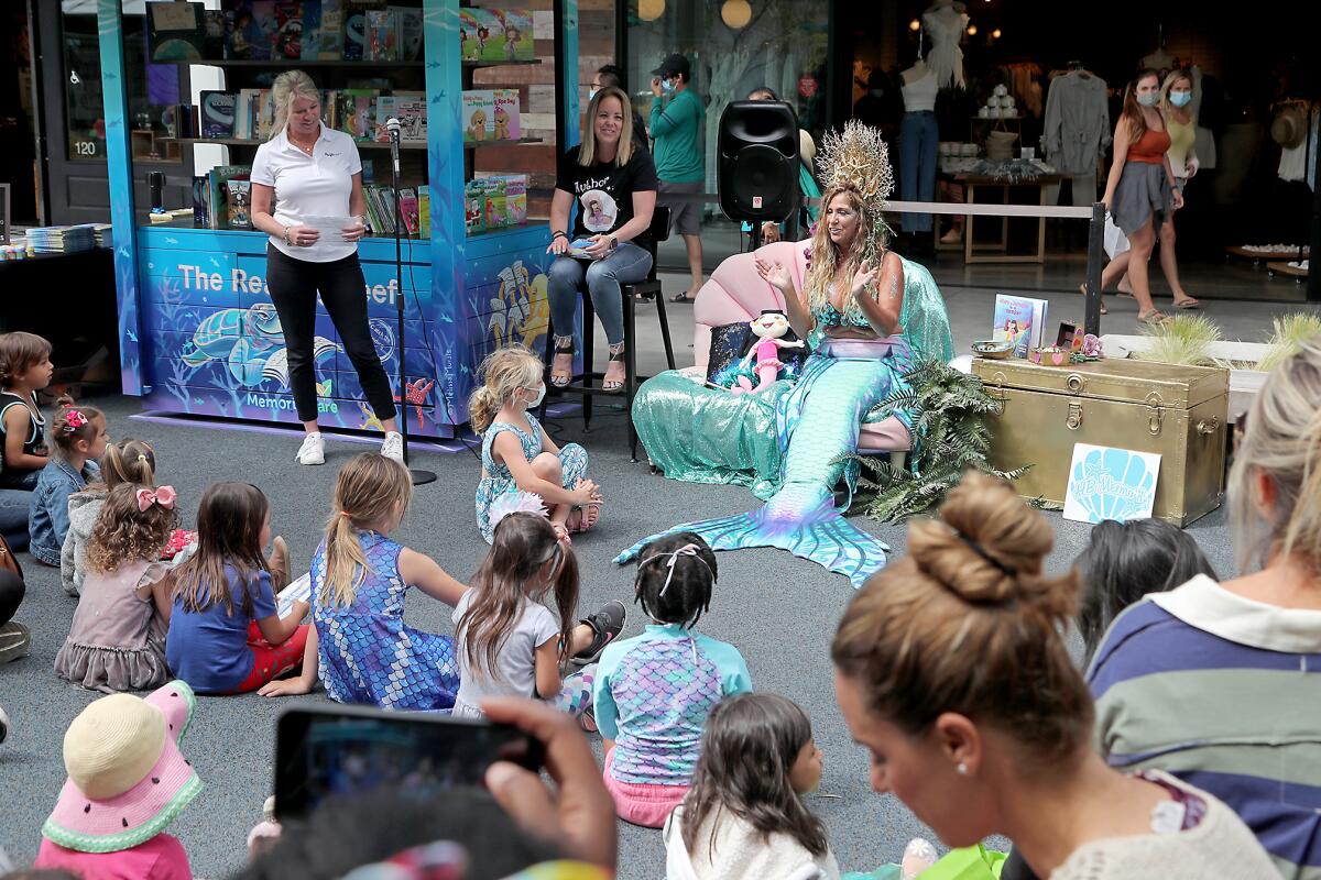 A member of the H.B. Mermaids speaks during the grand opening for the Reading Reef library at Pacific City.