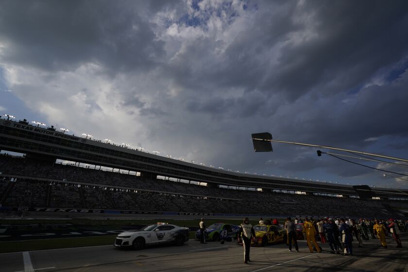 With clouds threatening lightning, a NASCAR Cup Series auto race field sits under a red flag delay at Texas Motor Speedway in Fort Worth, Texas, Sunday, Sept. 25, 2022. (AP Photo/LM Otero)