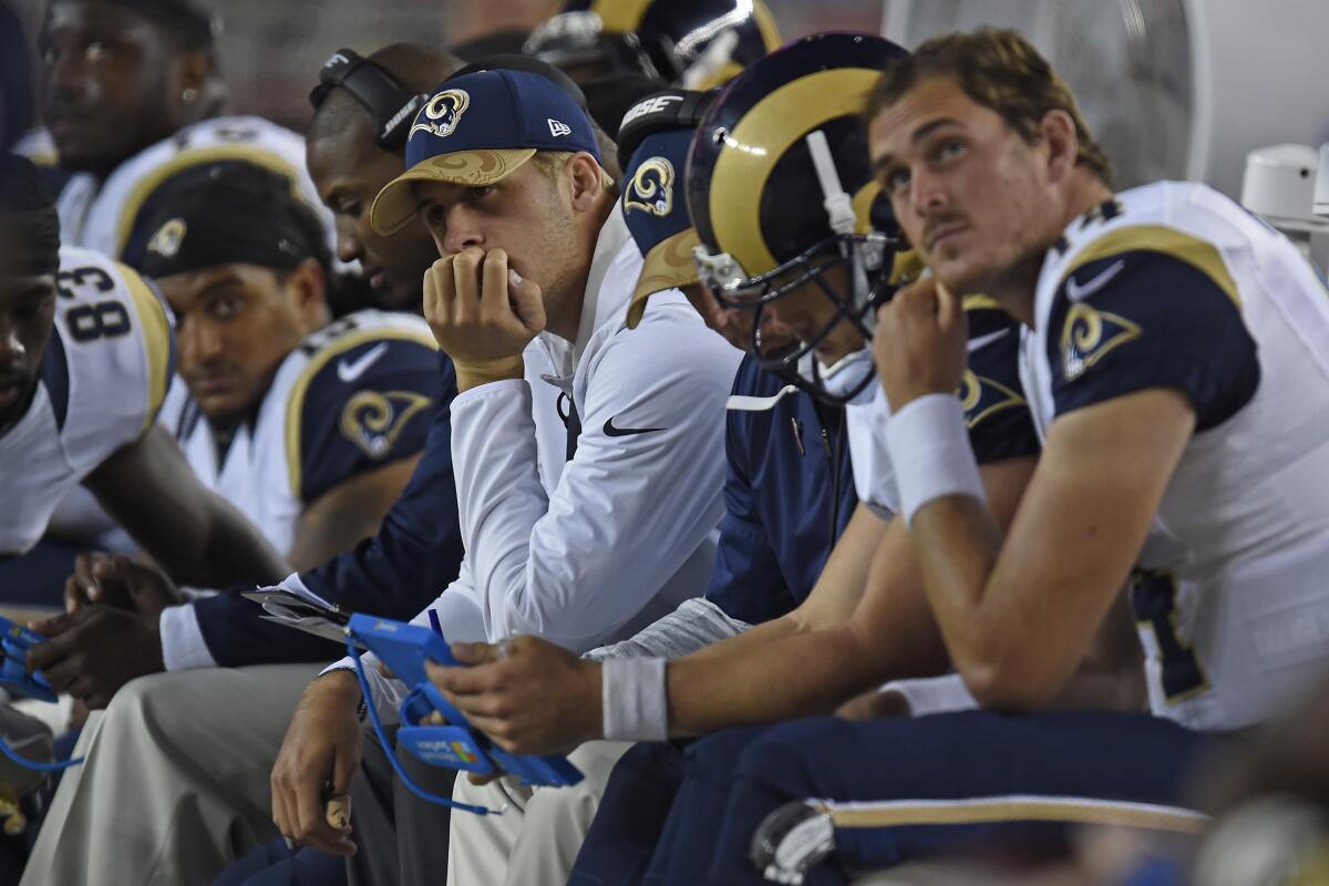 Jared Goff sits on the bench in street clothes, hand on chin,  while the Rams play at San Francisco in 2016.