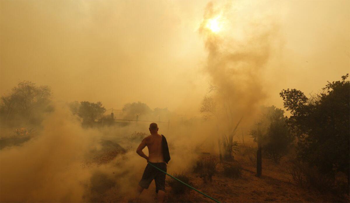 Sunland resident Jeff Dalton sprays water near his home as flames from the La Tuna fire approach.