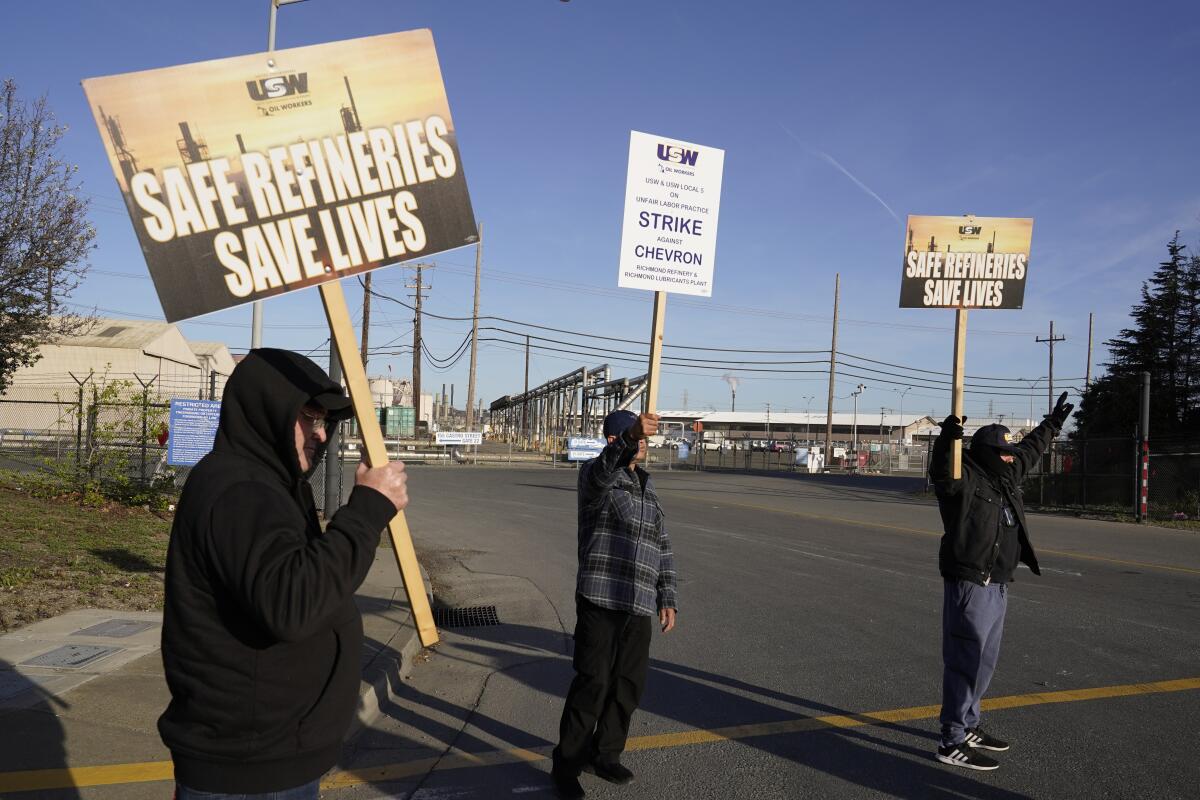 People hold picket signs that read, "Safe refineries save lives."