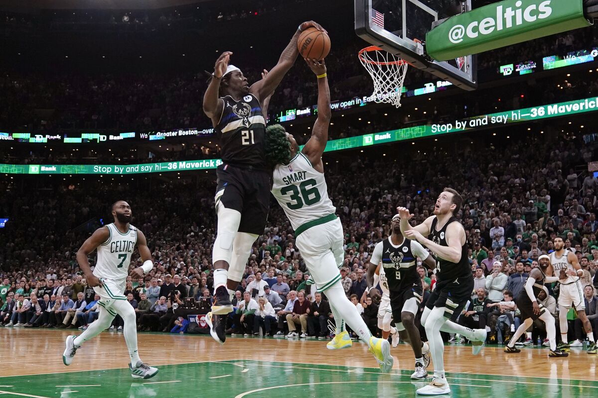 Milwaukee Bucks guard Jrue Holiday (21) blocks a shot by Boston Celtics guard Marcus Smart (36) in the final seconds of play during the second half of Game 5 of an Eastern Conference semifinal in the NBA basketball playoffs, Wednesday, May 11, 2022, in Boston. The Bucks won 110-107. (AP Photo/Charles Krupa)