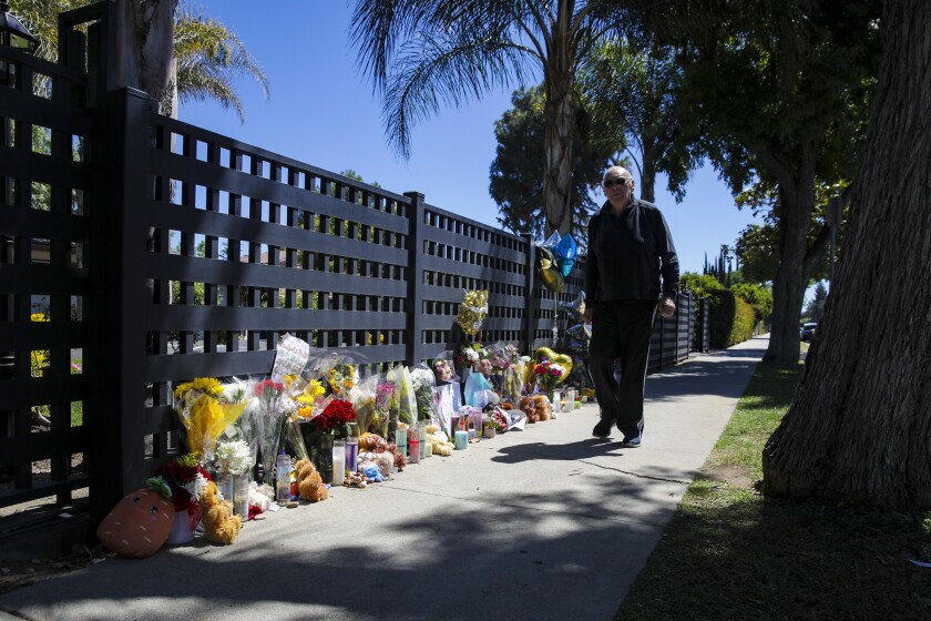 A man walks past flowers and candles of a makeshift memorial