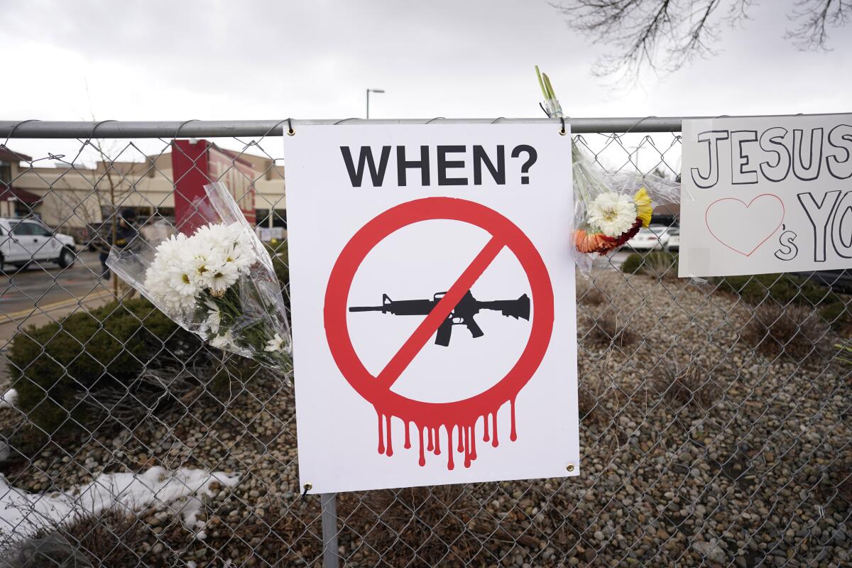 A sign hangs on a fence put up around the parking lot where a mass shooting took place in Boulder, Colo.