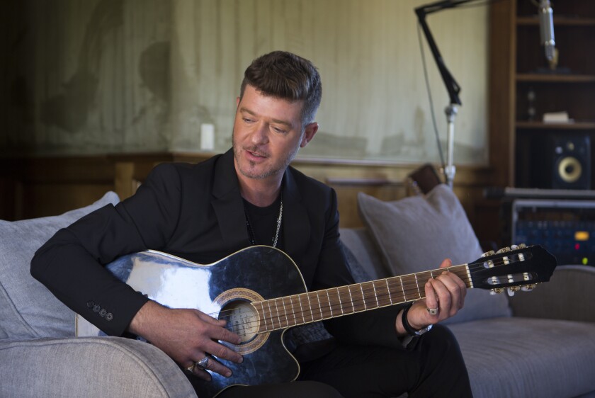 Robin Thicke seated with an acoustic guitar