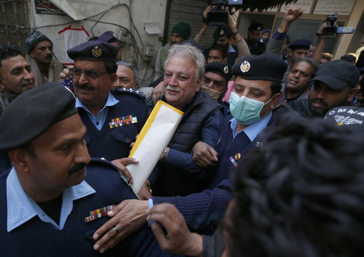 Police officers escort Pakistani journalist Mohsin Baig, center, for his court appearance, in Islamabad, Pakistan, Wednesday, Feb. 16, 2022. Police arrested Baig, a prominent journalist and government critic, at his home on unspecified charges on Wednesday, his colleagues and local media said. (AP Photo/Anjum Naveed)