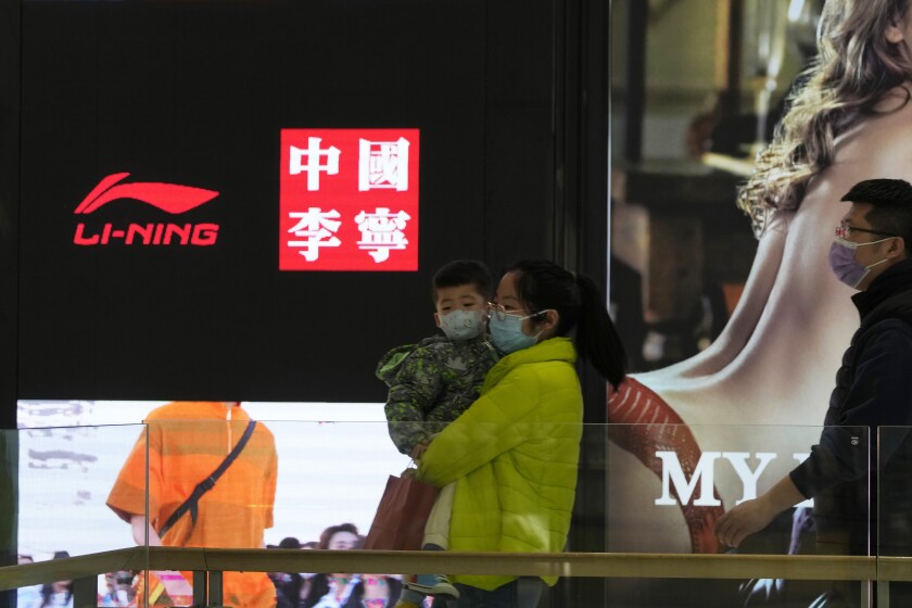 Visitors to a mall walk past signs of Chinese sports brand Li Ning on Wednesday, March 16, 2022, in Beijing. The U.S. customs agency says it is holding imported goods from Li Ning after an investigation indicated they were made by North Korean labor. U.S. law prohibits imports of goods made in North Korea or by North Korean citizens without proof they weren’t made by forced labor, according to a notice from the U.S. Customs and Border Protection in Washington. (AP Photo/Ng Han Guan)