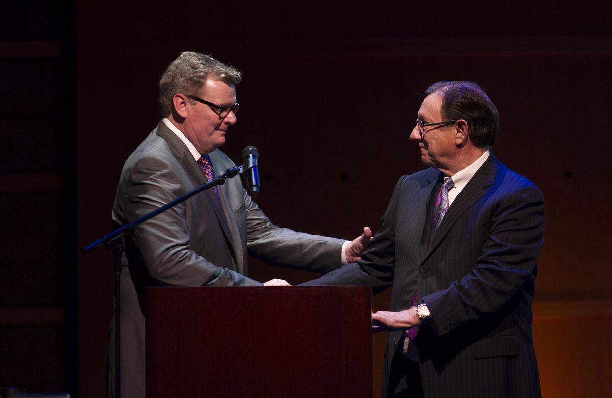 Former Costa Mesa Mayor Steve Mensinger shakes hands with Paul Folino.