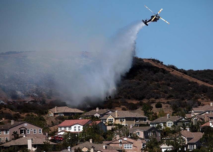A firefighting helicopter drops its load on the ridge near the Dos Vientos neighborhood in Newbury Park on Thursday afternoon.