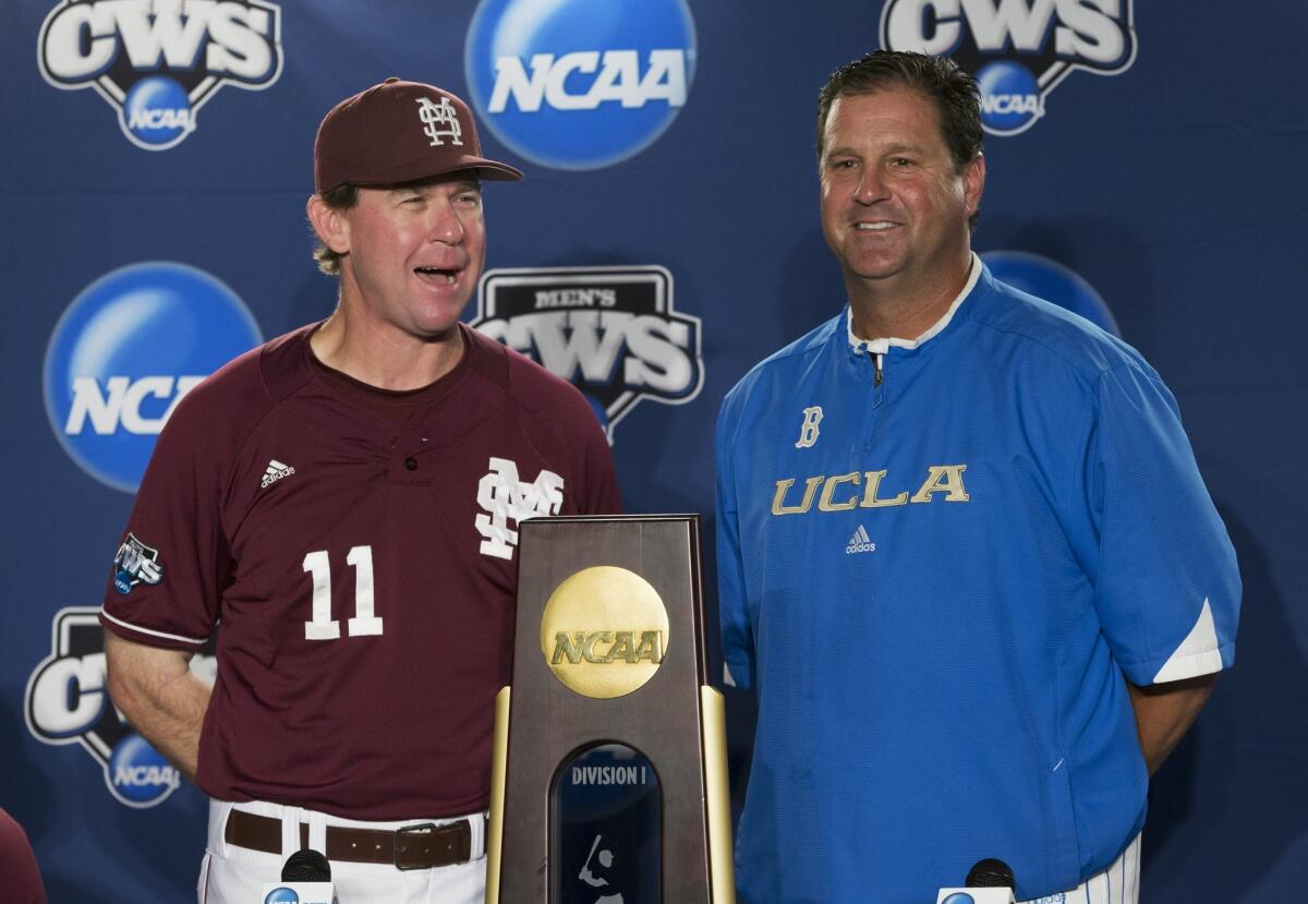Mississippi State coach John Cohen, left, and UCLA coach John Savage pose with the College World Series trophy before the start of a news conference Sunday.