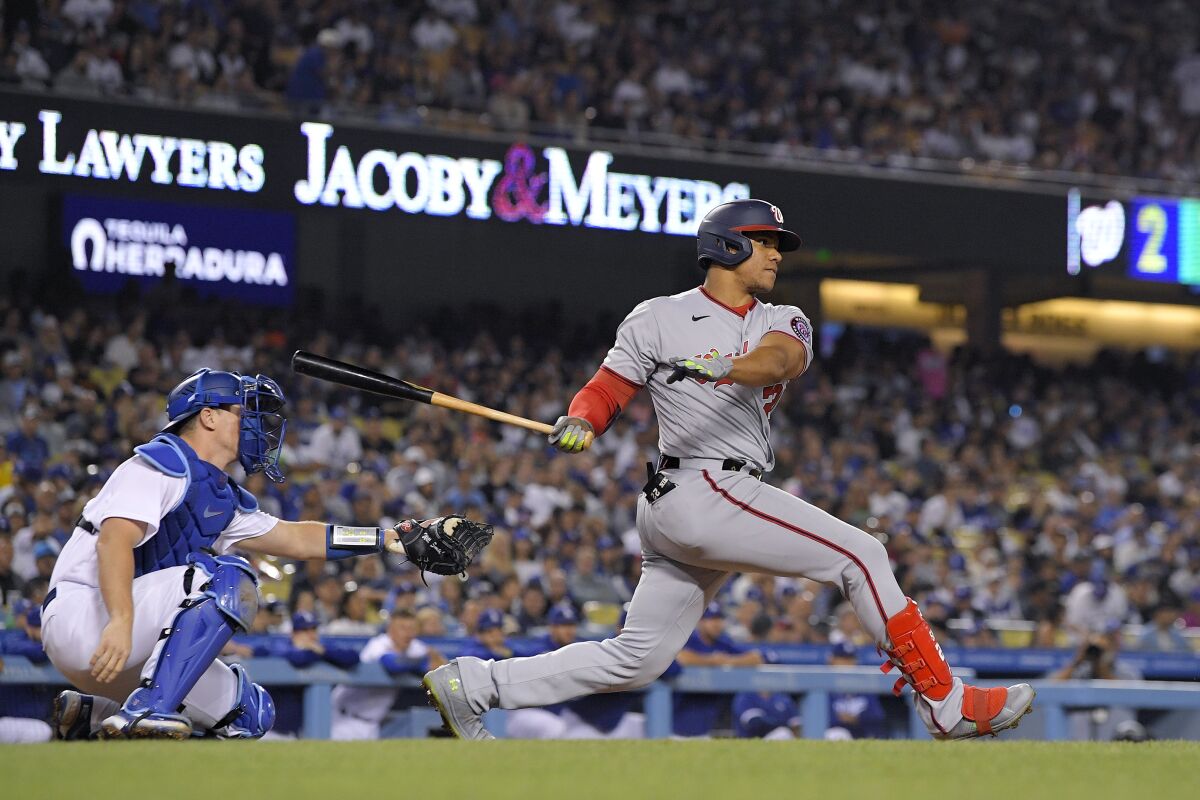Washington Nationals' Juan Soto hits a two RBI triple as Dodgers catcher Will Smith watches.