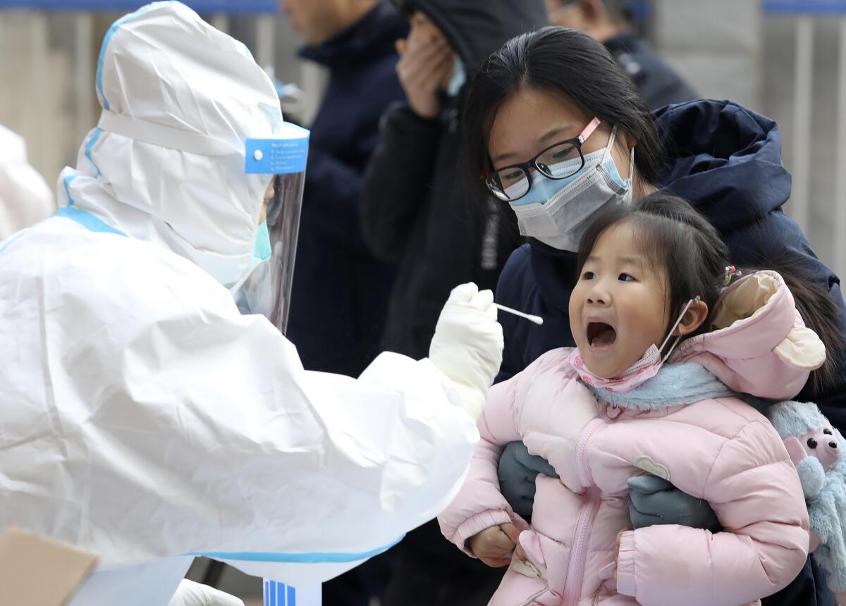 A worker in a protective suit takes a swab from a child for a coronavirus test in Shijiazhuang, China, on Jan. 12.