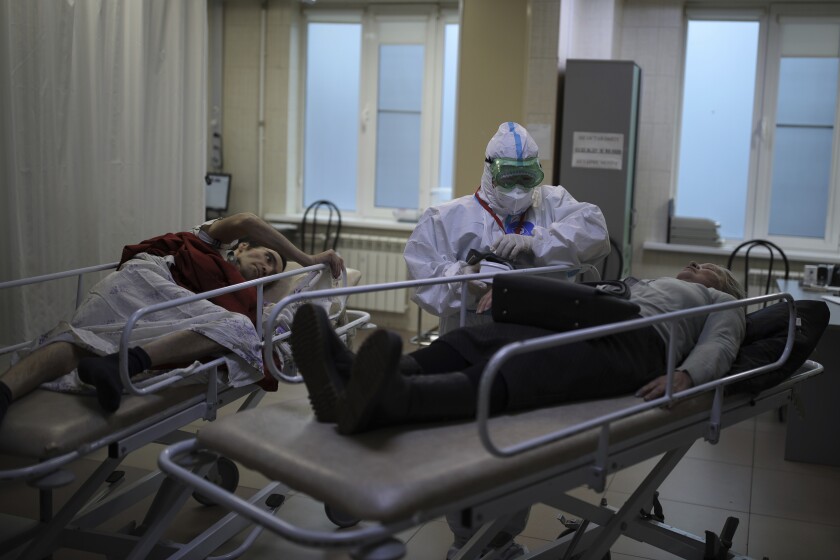Un médico con un traje especial para protegerse contra el coronavirus, mide la presión arterial de un paciente 