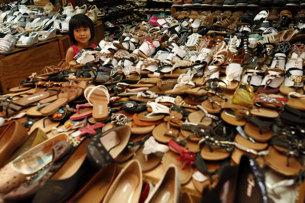 Viola Long, 4, is lost in a sea of shoes for sale at the swap meets at Saigon Plaza in Chinatown. (Genaro Molina / Los Angeles Times)