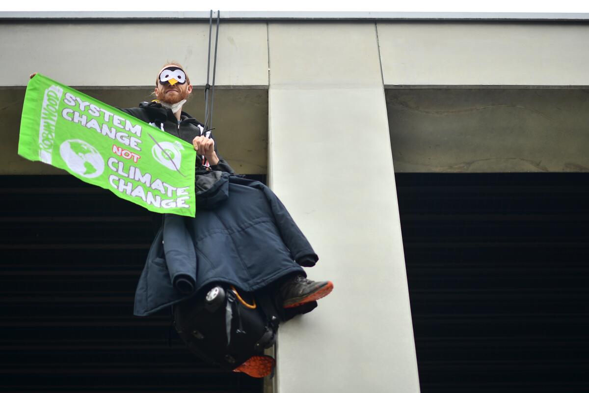 Un activista contra el cambio climático se cuelga de parte de la estructura