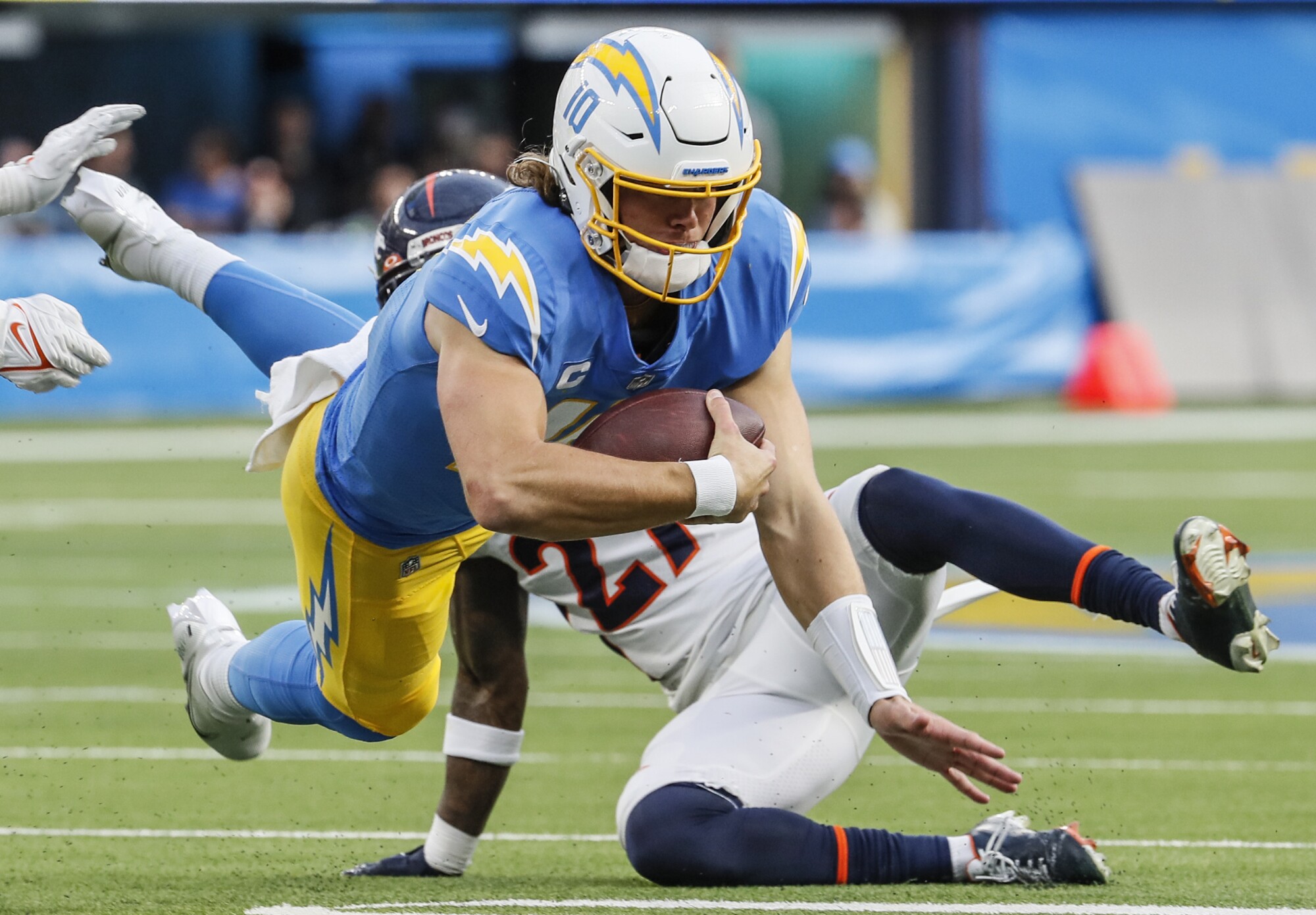 Chargers quarterback Justin Herbert dives for a first down in front of Denver Broncos cornerback Ronald Darby.