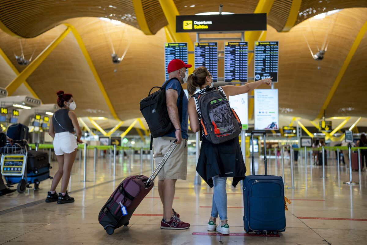 Passengers check the departure screen at the Adolfo Suarez-Barajas international airport in Madrid, Spain, Friday, July 9, 2021. Spain's top diplomat is pushing back against French cautions over vacationing on the Iberian peninsula. Southern Europe's holiday hotspots worry that repeated changes to rules on who can visit is putting people off travel. On Thursday, France's secretary of state for European affairs, Clement Beaune, advised people to "avoid Spain and Portugal as destinations" when booking their holidays because COVID-19 infections are surging there. (AP Photo/Manu Fernandez)