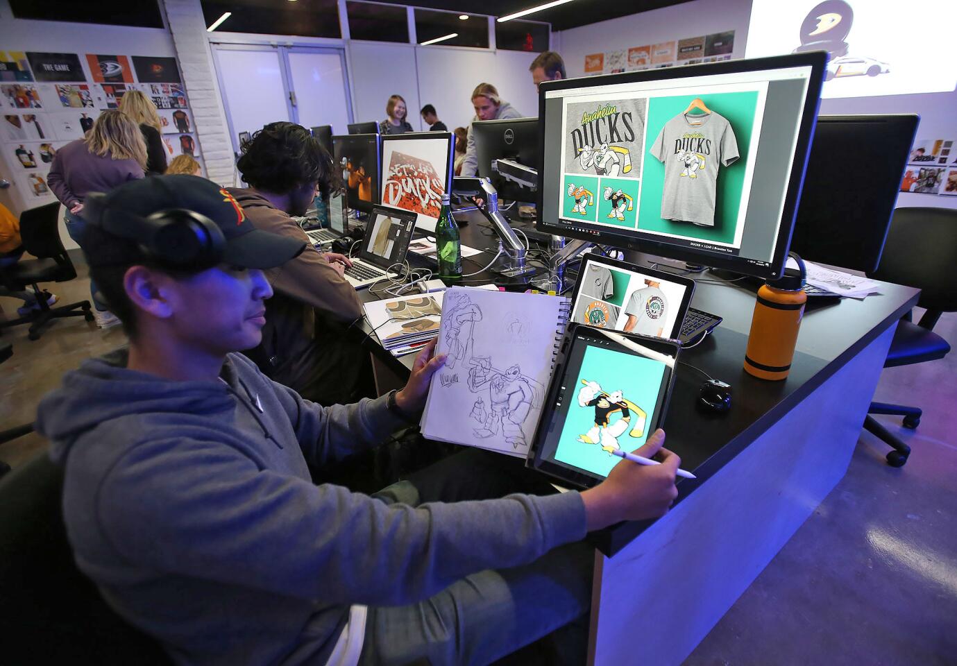 Art student Brandon Tam compares his final design of the Anaheim Ducks' Wild Wing mascot with the one in his sketchbook at his workstation at the Laguna College of Art + Design. For the past three semesters, seniors and juniors in graphic design and digital media have been selected for an honors class focused on creating promotional platforms for the Ducks.