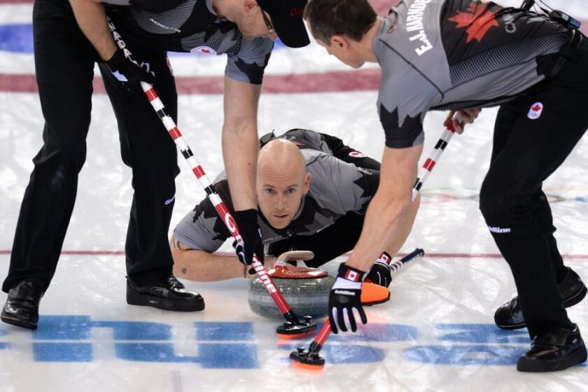 Canada's Ryan Fry, center, throws the stone while his team mates Ej Harnden, right, and Ryan Harnden brushruary 19, 2014. AFP PHOTO / ANDREJ ISAKOVIC