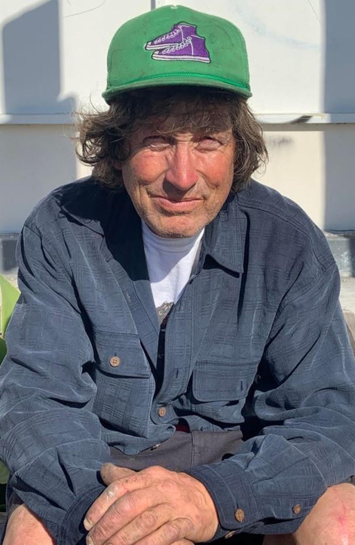 A man in a baseball cap sits outdoors