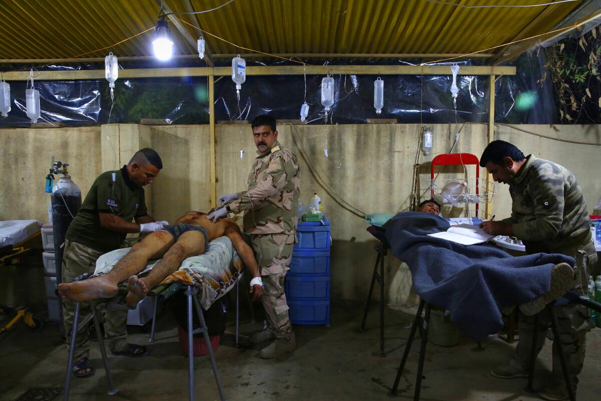 Murtada Abdul Amir, right, was struck in the shoulder by the same bullet that hit his friend Muaz Hameed Hussein, left. Capt. Osama Fuad Rauf checks Hussein's status.