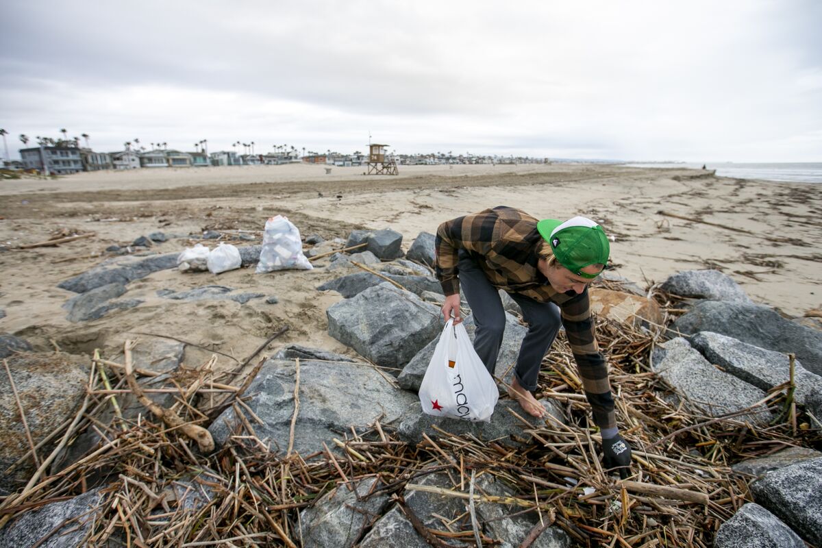Spencer Clark picks up small pieces of trash along the jetty at the mouth of the Santa Ana River.