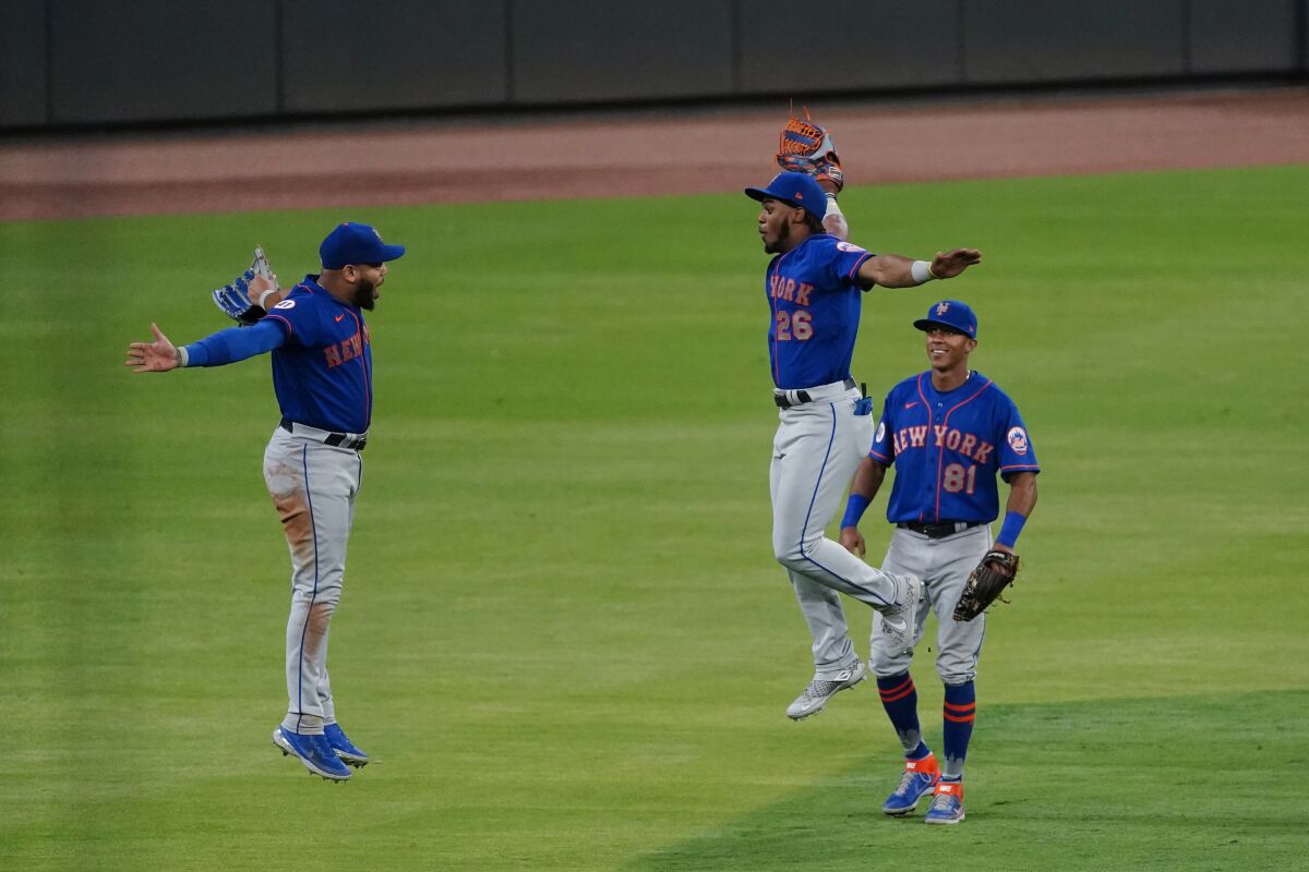 New York Mets outfielders Khalil Lee (26) Dominic Smith, left, and Johneshwy Fargas (81) celebrate the team's 4-3 win over the Atlanta Braves in a baseball game Tuesday, May 18, 2021, in Atlanta. (AP Photo/John Bazemore)