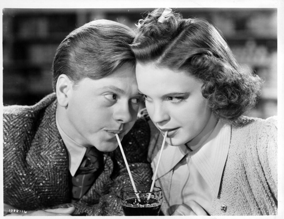 Mickey Rooney and Judy Garland sharing a soda together as they stare into each other's eyes in a scene from the 1943 film "Babes in Arms."