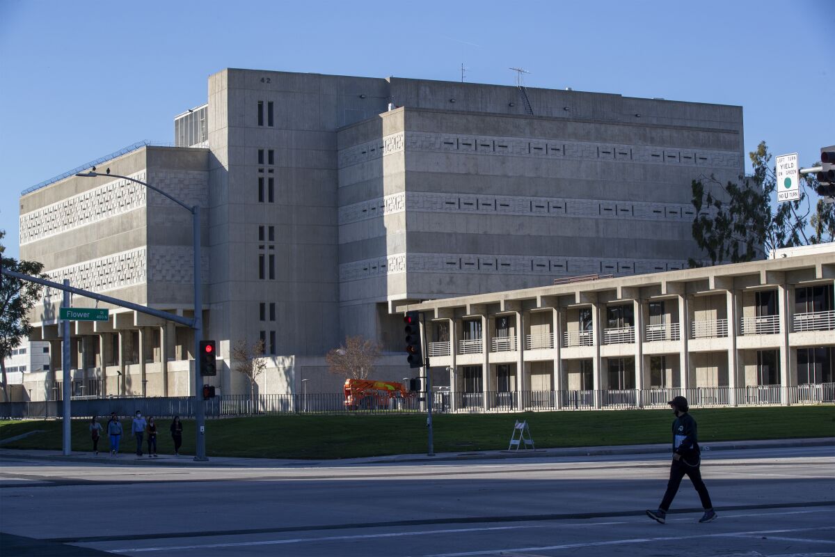 A pedestrian walks past a multistory concrete building