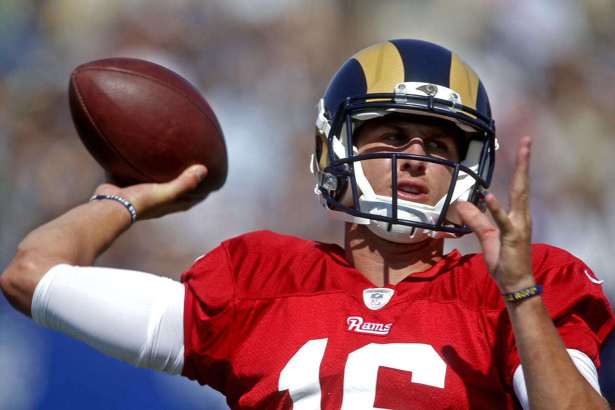 A quarterback in a red Rams jersey throws a pass.